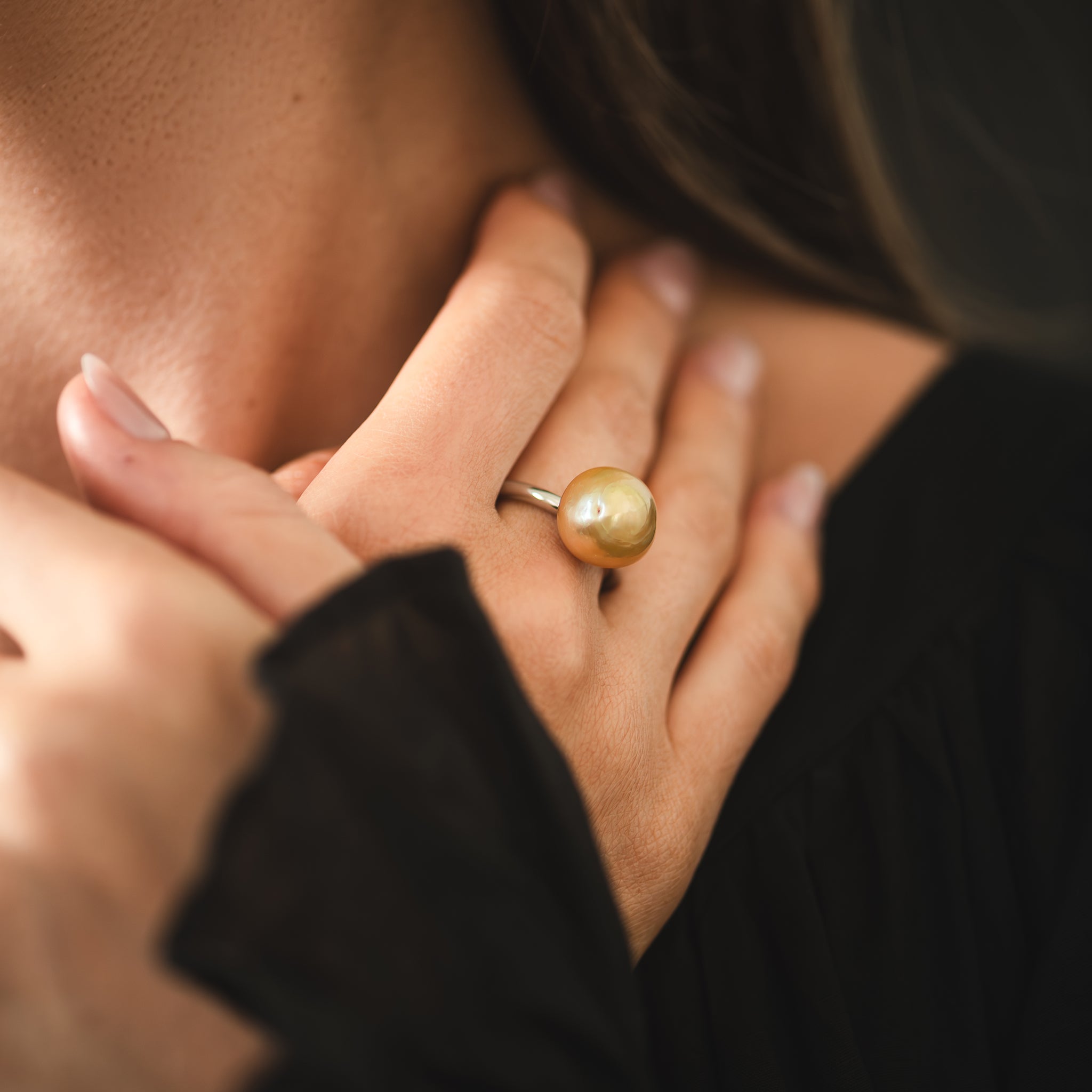 Hand selected unique golden South Sea pearl, set on a white gold ring with high polish finish, worn on a woman&#39;s middle finger.